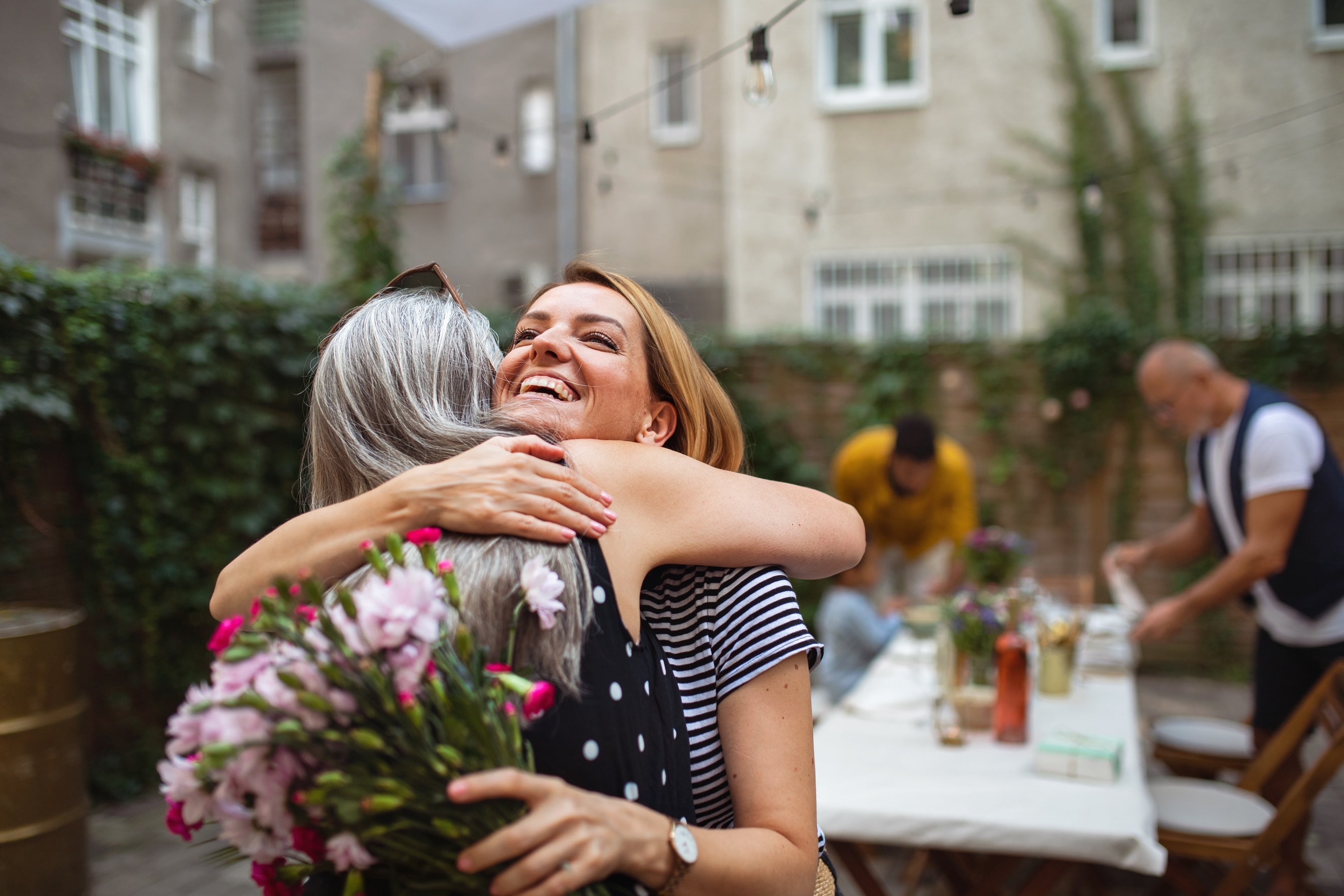 Daughter gifting a  mother with a set of flowers 